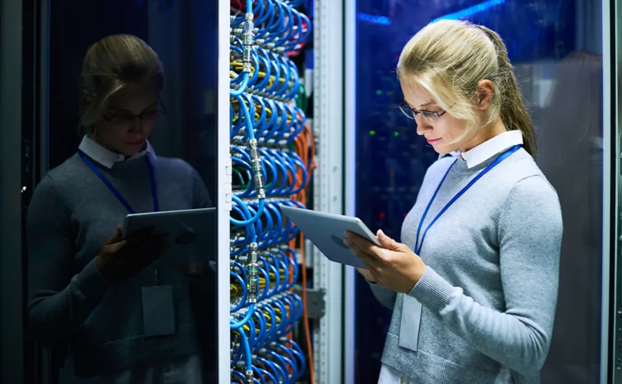 Engineer checking server and endpoint management on a tablet in a server room