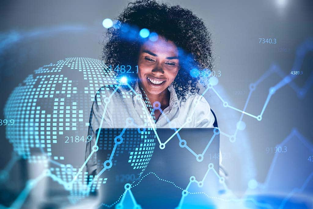 Cheerful young African American woman trader using laptop in blurry office with double exposure of blurry financial chart and planet hologram. Concept of stock market and technology. Toned image