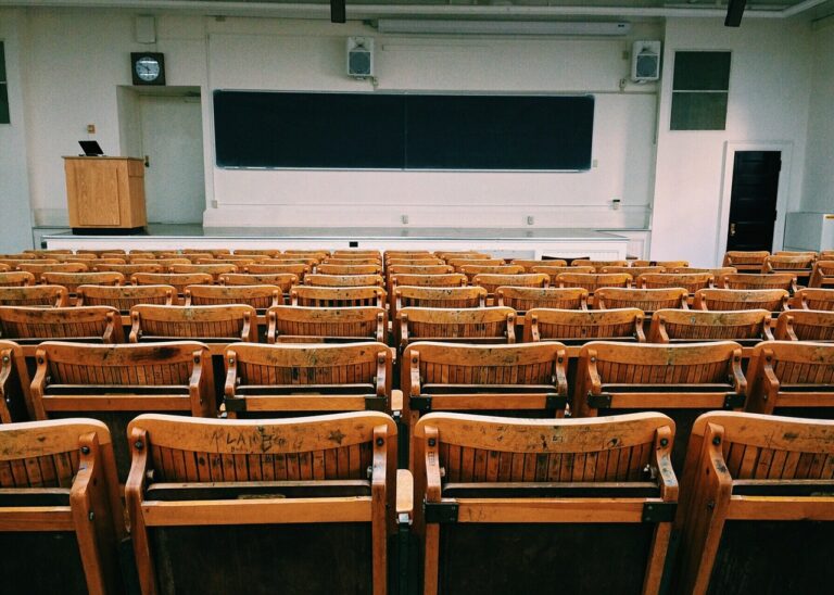 View of a classroom with chalkboard, bench seats, and teacher's podium