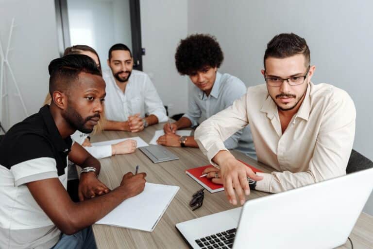 woman and men at a table around a laptop for training