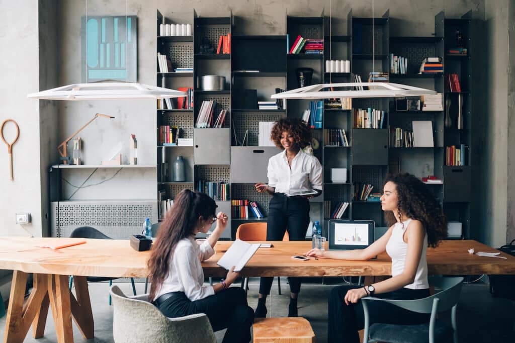 Three young colleagues using technology in a loft office who are in need of cyber insurance coverage