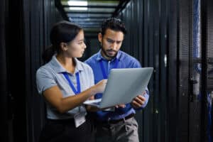 man and woman looking at laptop in server room