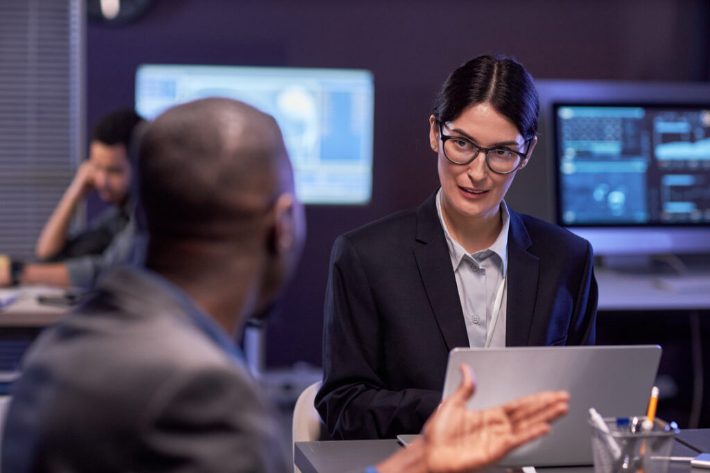 Women giving cyber security consulting to man in office